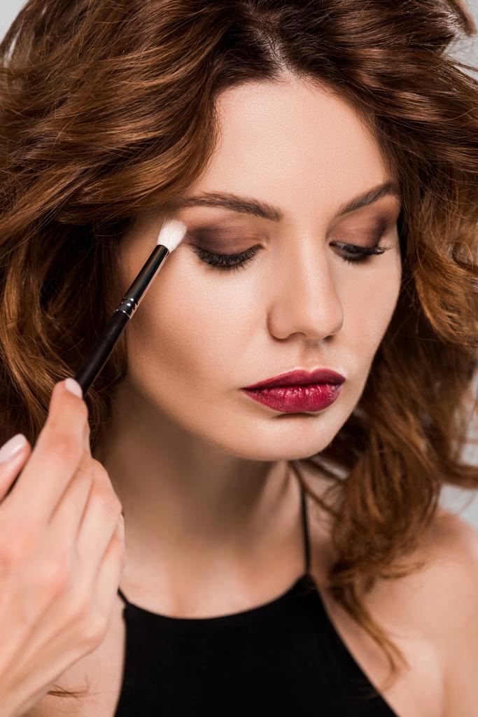 cropped view of makeup artist apply eye shadow on beautiful woman isolated on grey  - Photo, Image