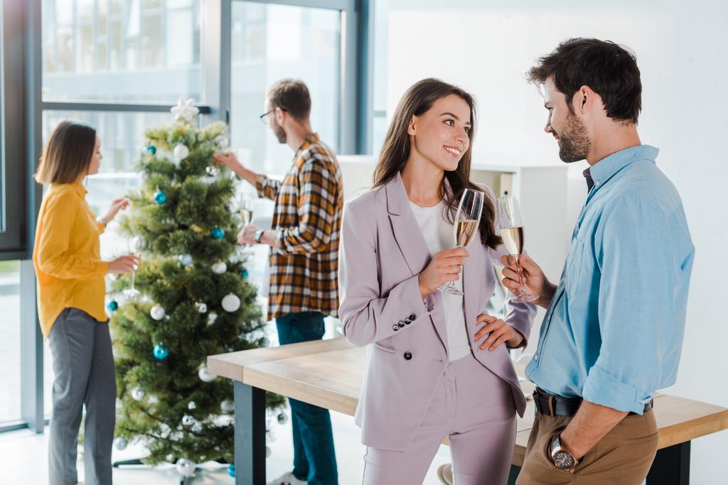focus selettivo di uomo d'affari e donna d'affari con bicchieri di champagne vicino a colleghi multiculturali e albero di Natale
  - Foto, immagini