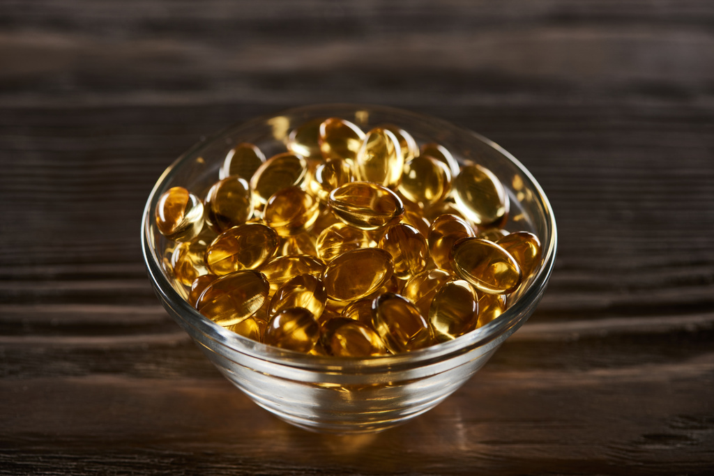 golden fish oil capsules scattered on wooden table - Photo, Image
