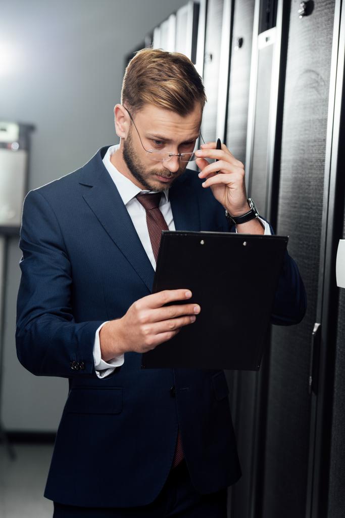красивый бизнесмен трогает очки, глядя на планшет
  - Фото, изображение