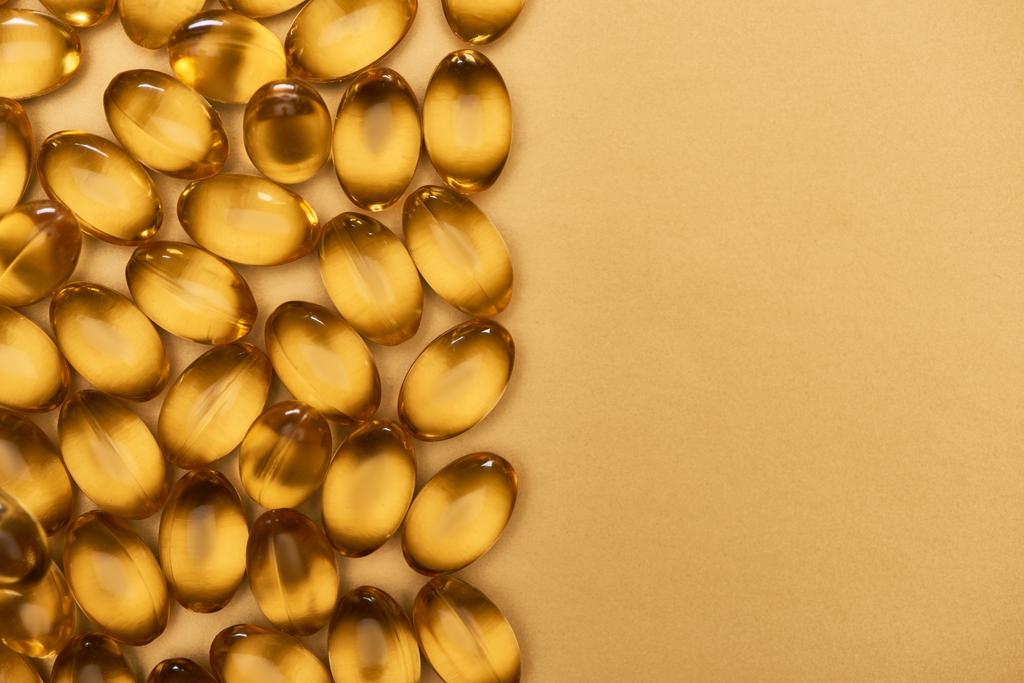 vista superior de cápsulas de aceite de pescado brillante dorado sobre fondo amarillo con espacio para copiar
 - Foto, imagen