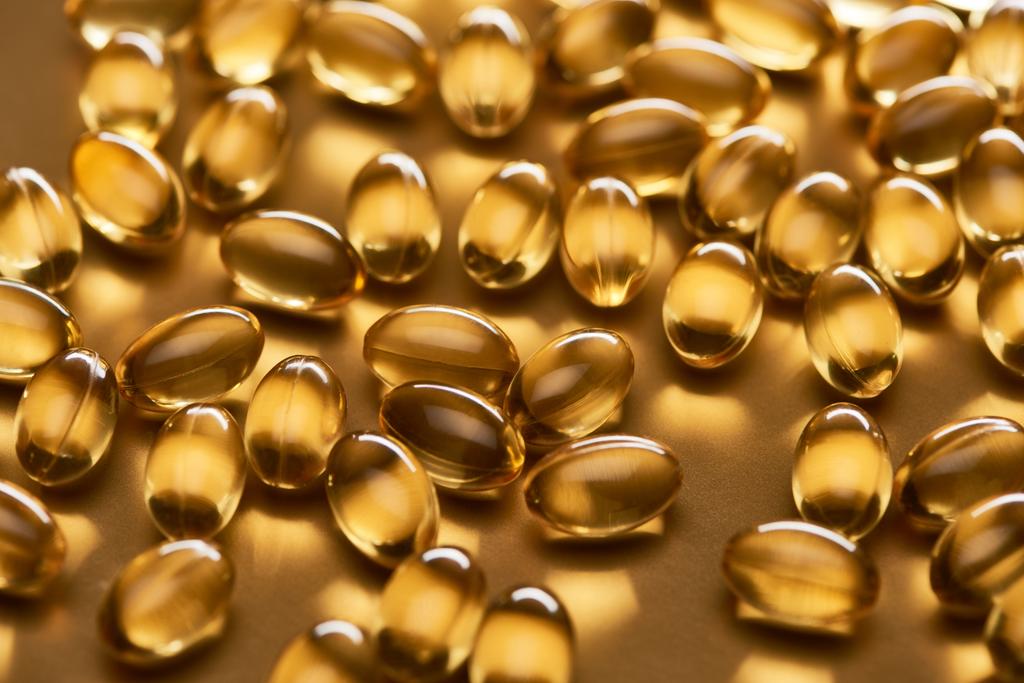 shiny fish oil capsules on golden background - Photo, Image
