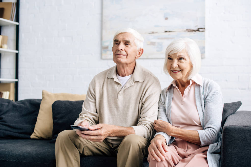 sorrindo marido e mulher assistindo tv e sentado no sofá no apartamento
  - Foto, Imagem