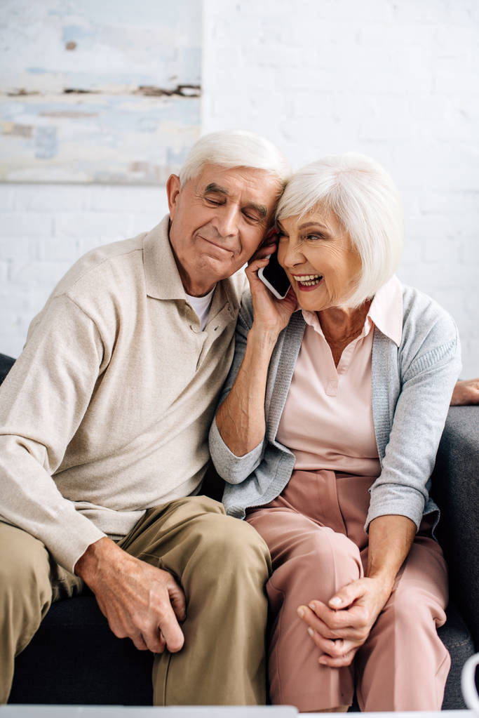 чоловік і усміхнена дружина розмовляють на смартфоні в квартирі
  - Фото, зображення