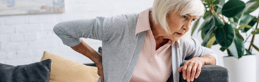 colpo panoramico di donna anziana che ha mal di schiena in appartamento
  - Foto, immagini