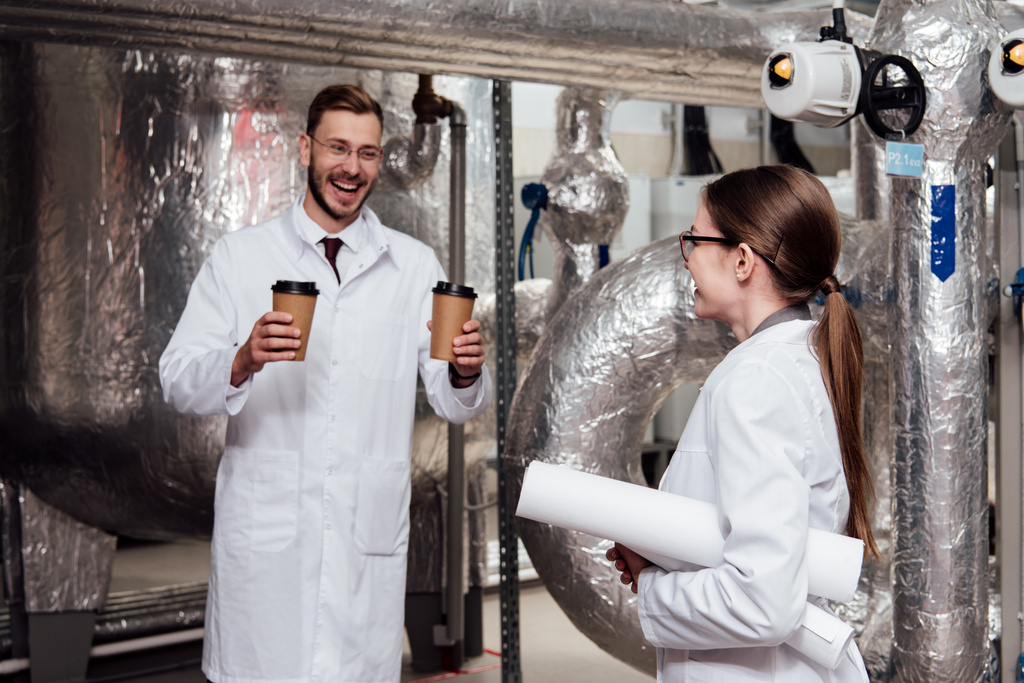веселый инженер держит бумажные стаканчики рядом с счастливым коллегой в очках
  - Фото, изображение