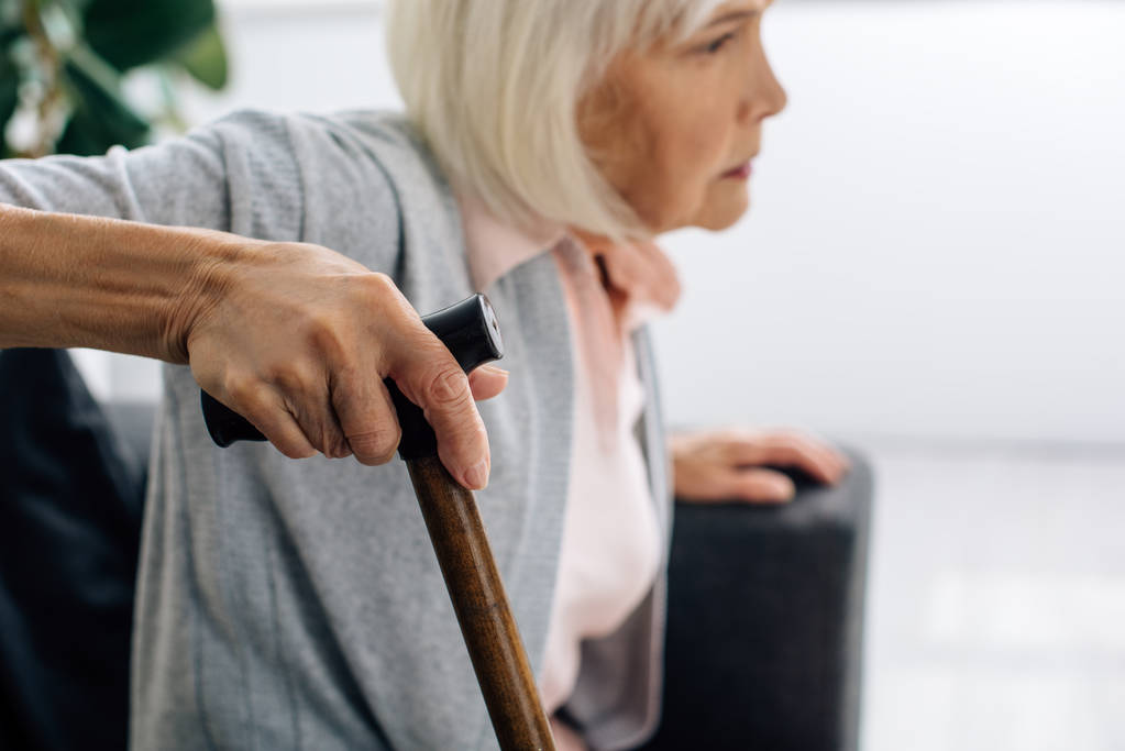 селективный фокус пожилой женщины с деревянной тростью в квартире
  - Фото, изображение