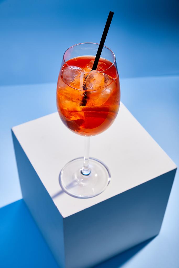 vista de alto ângulo de cocktail Aperol Spritz com palha em vidro sobre fundo azul
  - Foto, Imagem