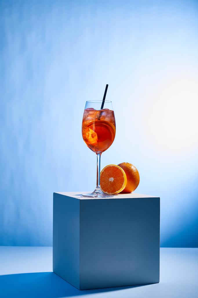 cocktail Aperol Spritz met rietje in glas en sinaasappels op blauwe achtergrond  - Foto, afbeelding