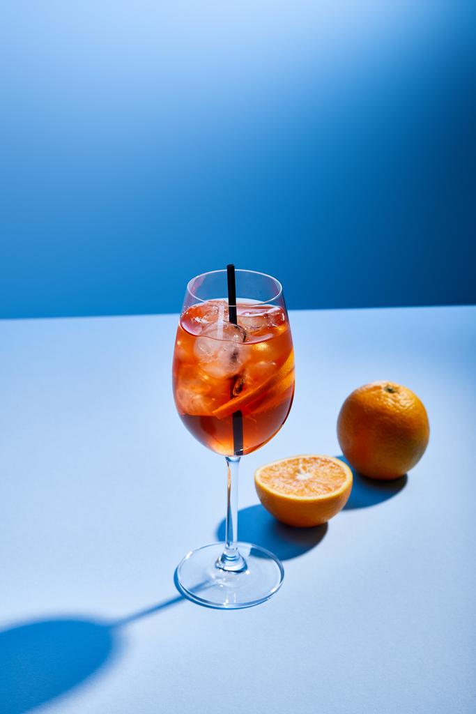 Bardakta saman ve mavi arka planda portakallı Aperol Spritz kokteyli.  - Fotoğraf, Görsel