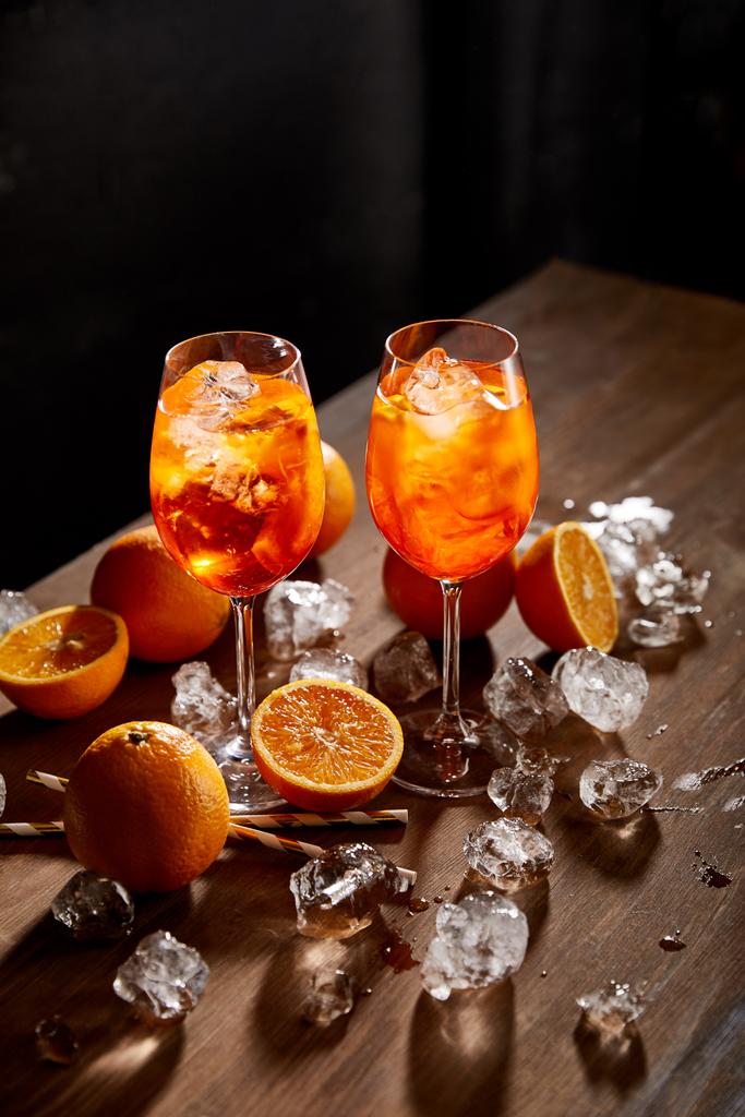 Aperol Spritz en verres, oranges et glaçons sur fond noir
  - Photo, image