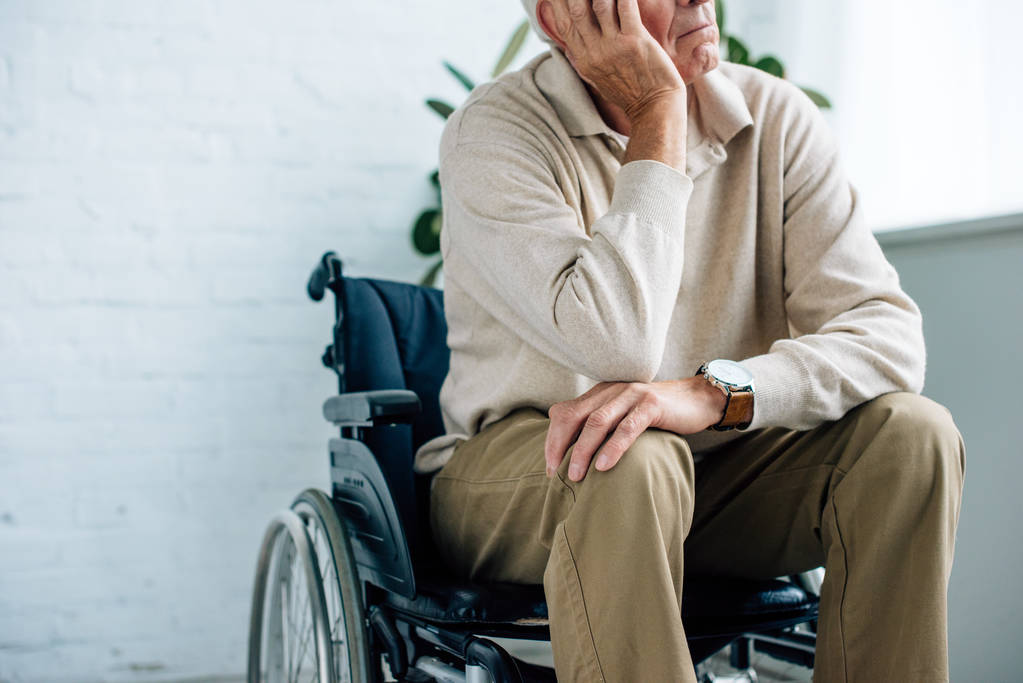 vue recadrée de l'homme âgé assis en fauteuil roulant dans l'appartement
  - Photo, image