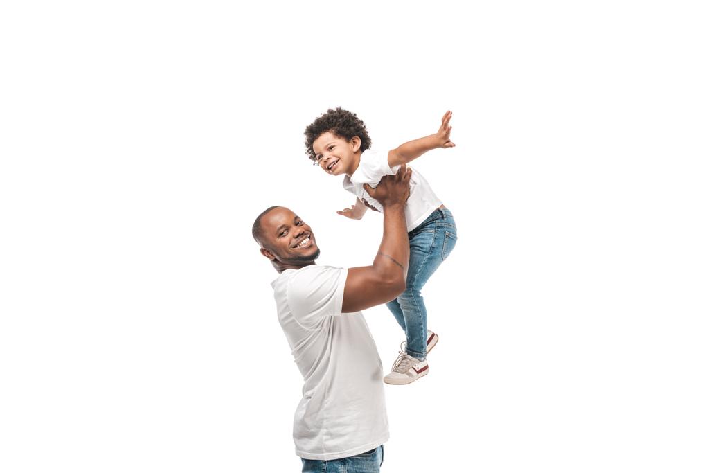 szczęśliwy Afrykanin amerykański człowiek trzyma uroczy syn nad głową i uśmiecha się do kamery odizolowany na biały - Zdjęcie, obraz