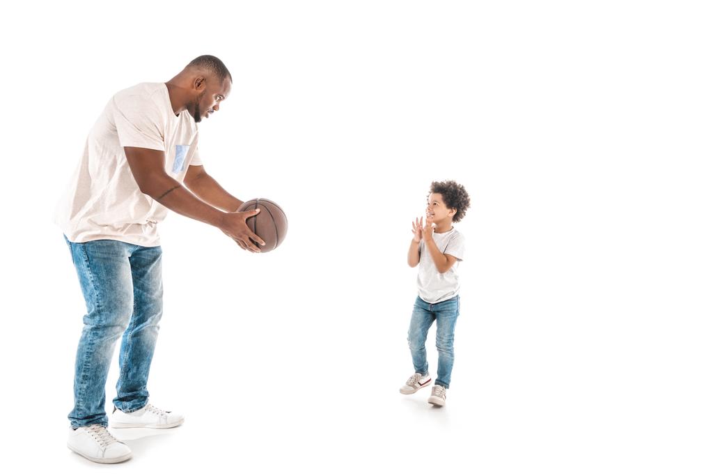 schöner afrikanisch-amerikanischer Mann zeigt seinem entzückenden Sohn Basketball auf weißem Hintergrund - Foto, Bild