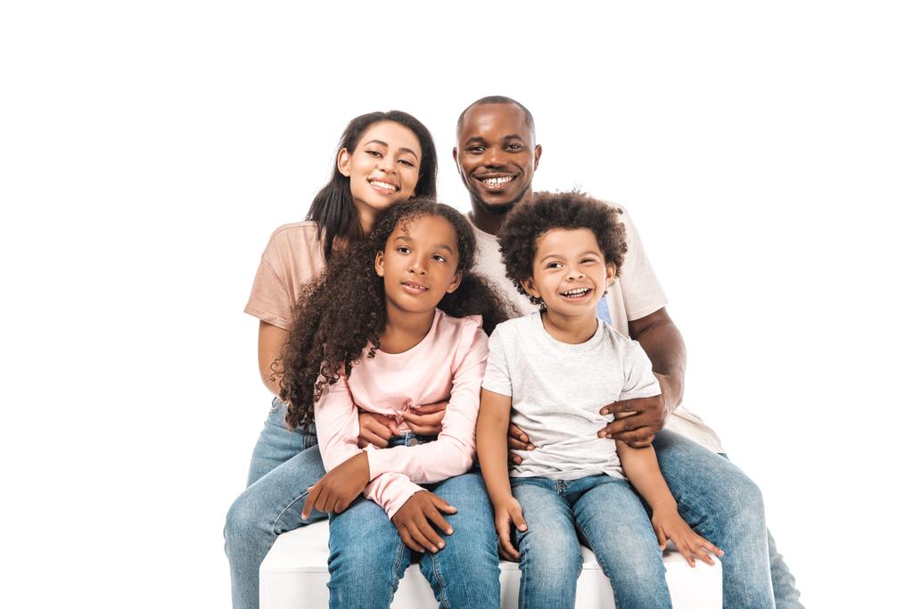 šťastný africký americký manželka a manžel objímání rozkošné děti, zatímco sedí izolovaný na bílém - Fotografie, Obrázek