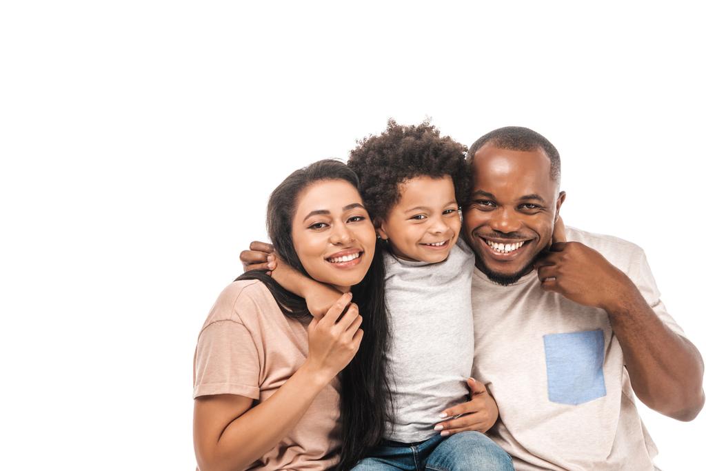 gelukkig Afrikaans amerikaans jongen knuffelen ouders en glimlachen op camera geïsoleerd op wit - Foto, afbeelding