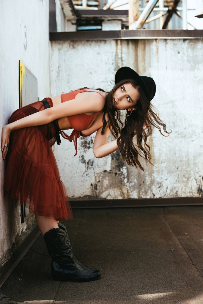 chica de moda posando en falda roja, sujetador y sombrero en el techo
 - Foto, imagen