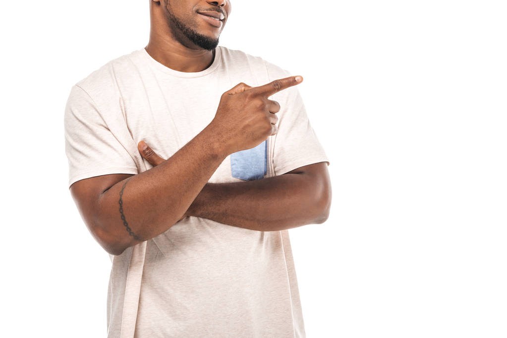 μερική άποψη του χαμογελαστού Αφροαμερικανού άνδρα που δείχνει μακριά με το δάχτυλο που απομονώνεται στο λευκό   - Φωτογραφία, εικόνα