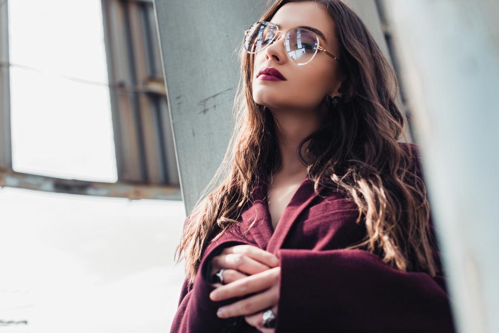 elegant young woman posing in trendy burgundy suit and sunglasses on urban roof  - 写真・画像