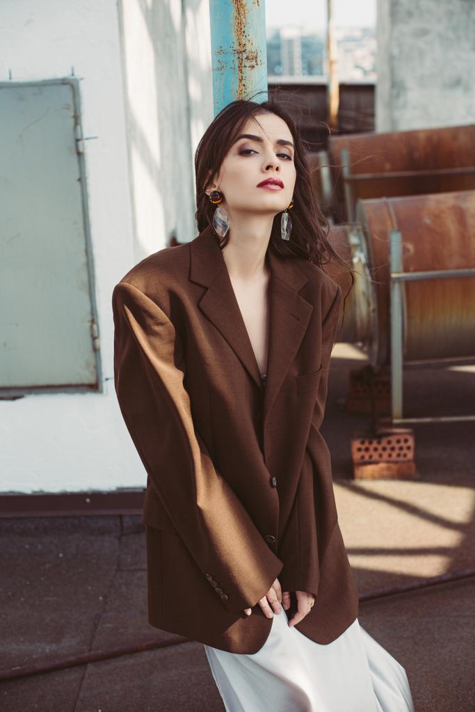 gyönyörű elegáns lány pózol selyem ruha és barna kabát a tetőn - Fotó, kép