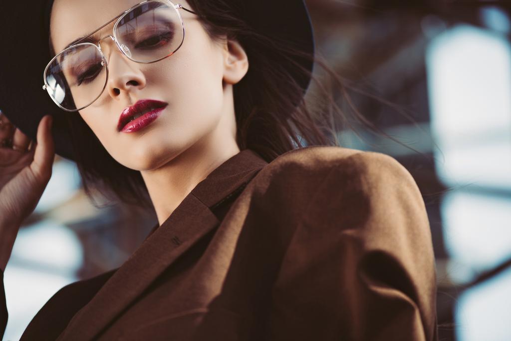 элегантная молодая женщина в шляпе, очках и коричневой куртке на крыше
 - Фото, изображение