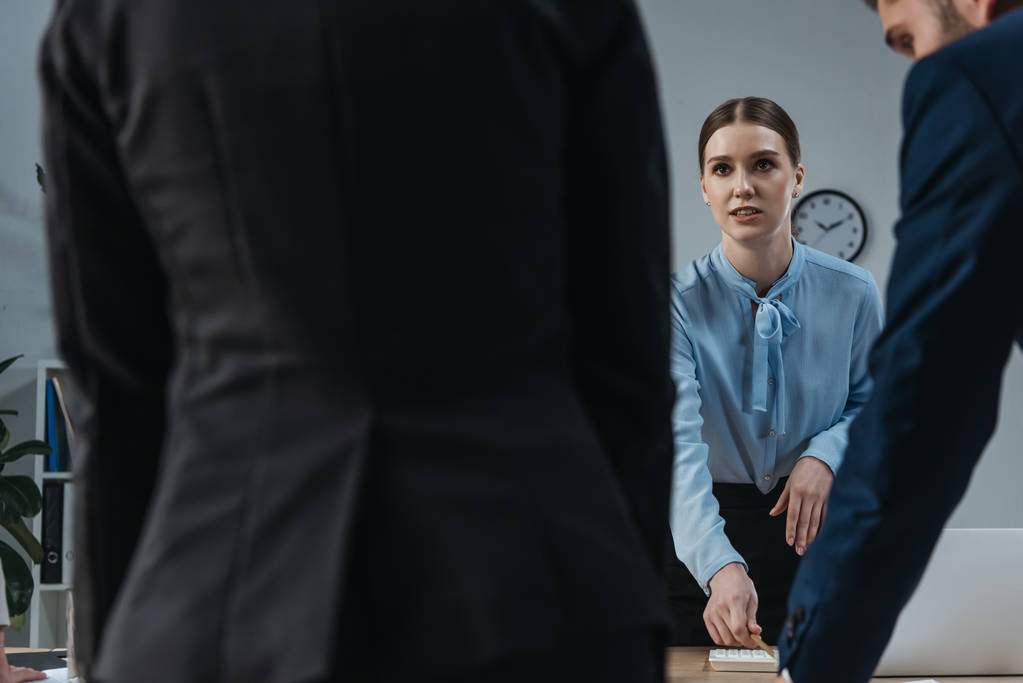 selective focus of young businesswoman looking at colleagues in meeting room - Photo, Image