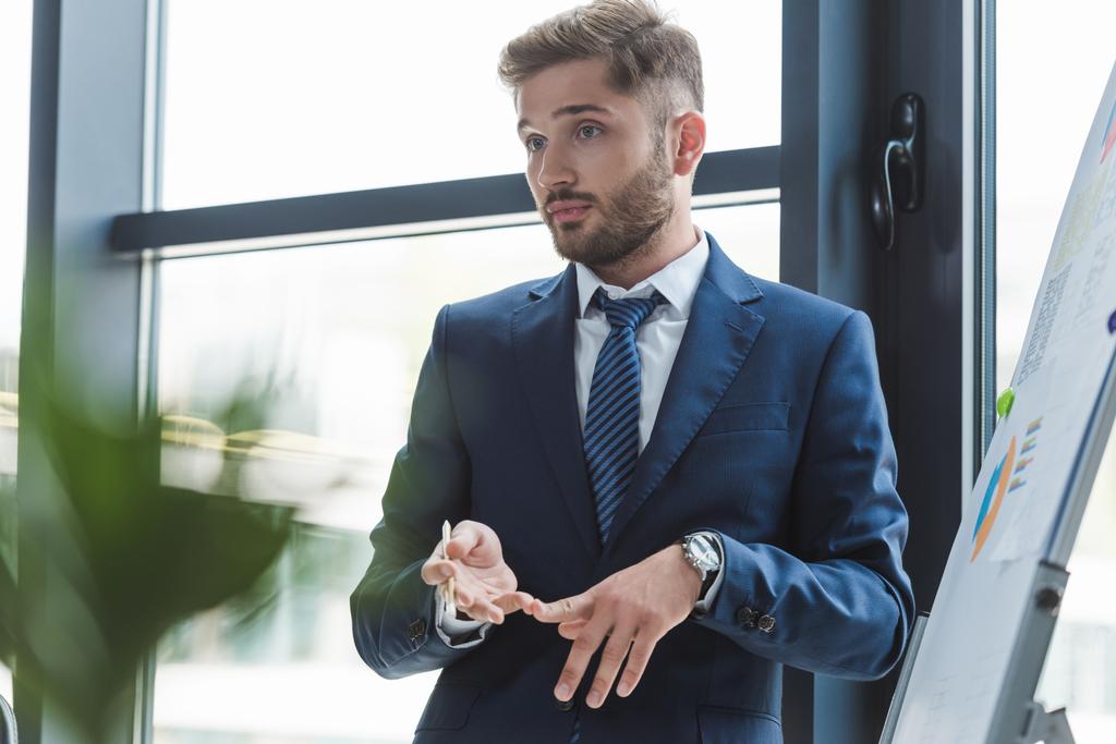 вибірковий бізнесмен підраховує пальцями, стоячи біля фліпчарт на діловій зустрічі
 - Фото, зображення
