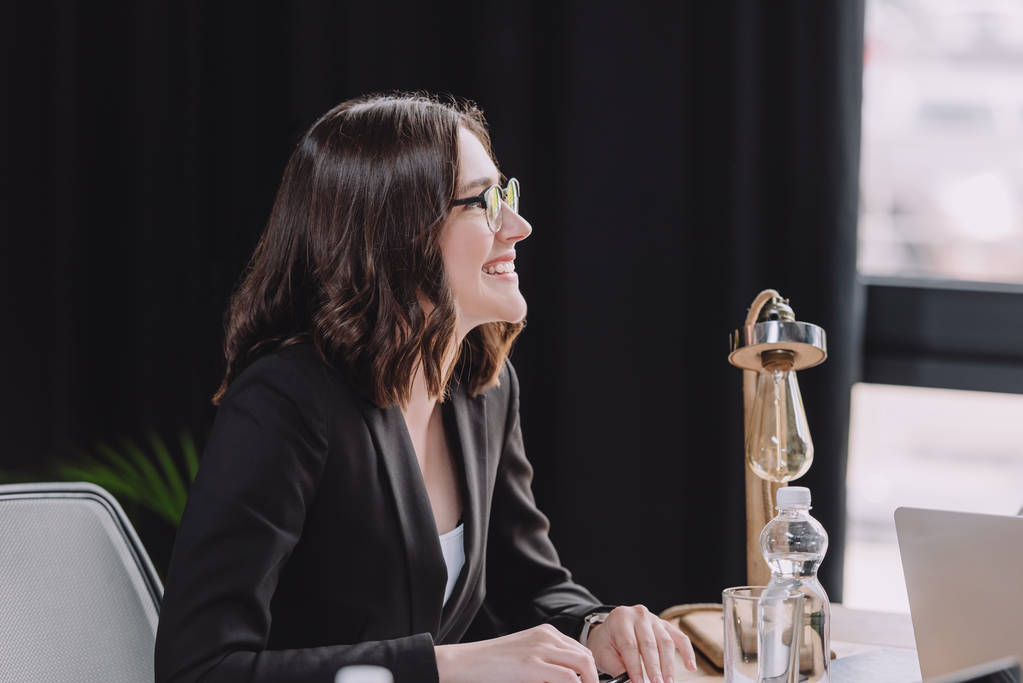 young businesswoman in glasses smiling during business meeting  - Photo, Image