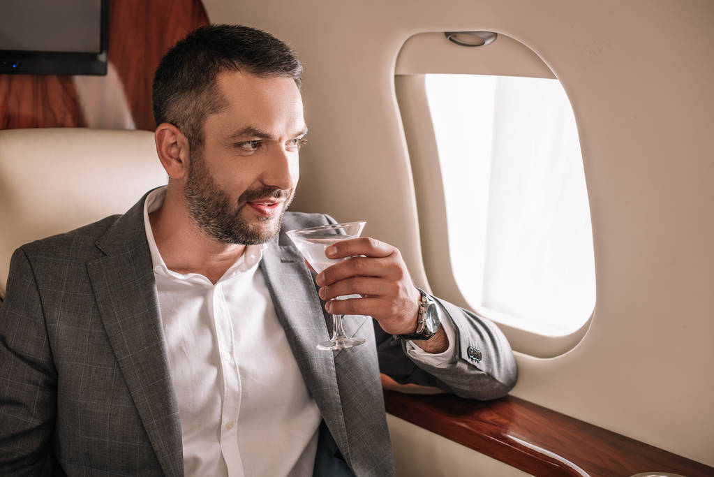 schöner Geschäftsmann mit Martini-Glas und Drink im Privatjet  - Foto, Bild