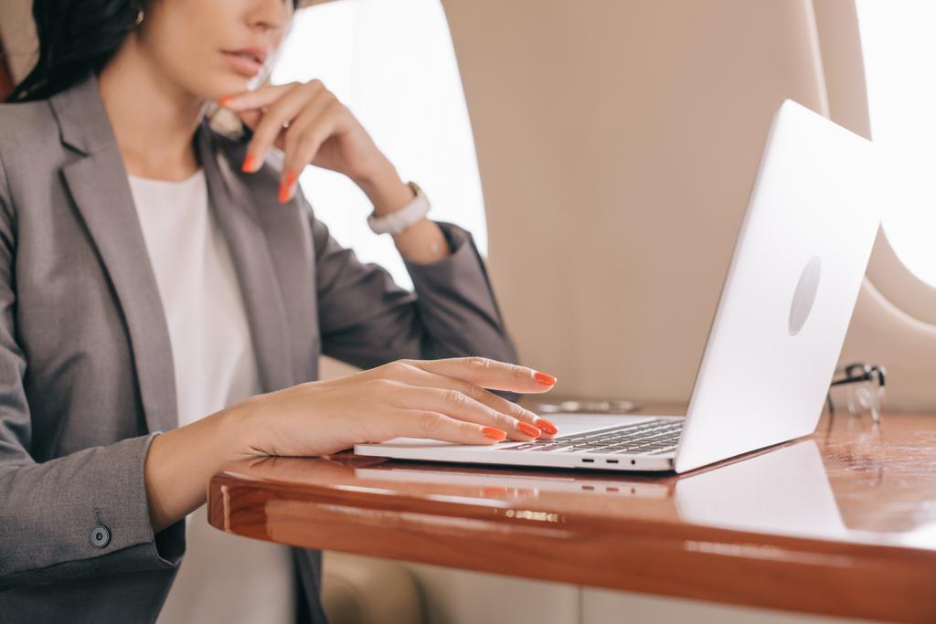 vista recortada de la mujer de negocios utilizando el ordenador portátil en jet privado
  - Foto, Imagen