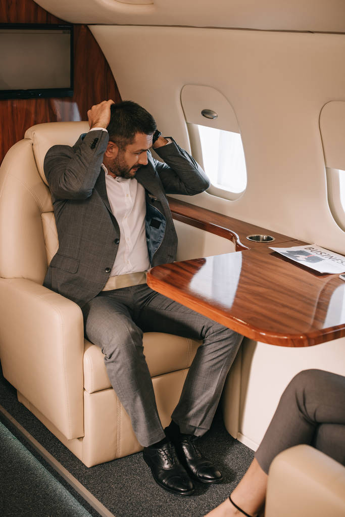 髭を生やしたビジネスマンが飛行機の中で座っている姿を切り取り  - 写真・画像