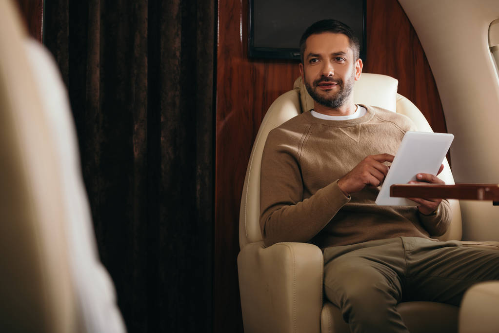 enfoque selectivo de hombre barbudo guapo utilizando tableta digital en jet privado
  - Foto, Imagen