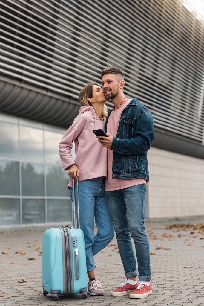Viajando. pareja usando el teléfono, esperando transporte cerca del aeropuerto
. - Foto, Imagen
