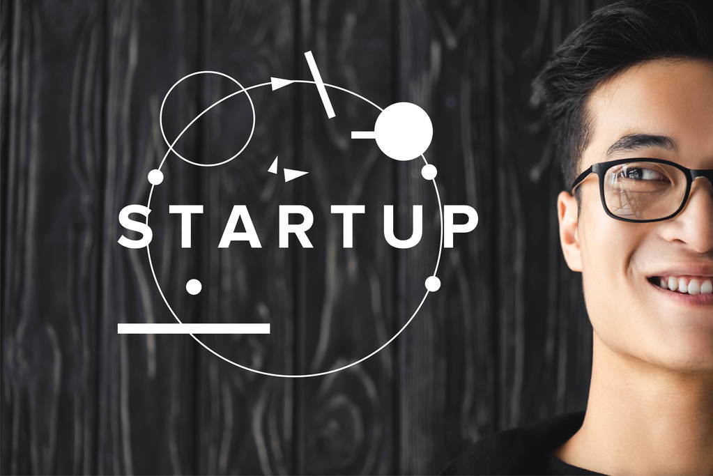 обрезанный вид улыбающегося азиатского человека в очках и иллюстрация с буквами стартапа
  - Фото, изображение