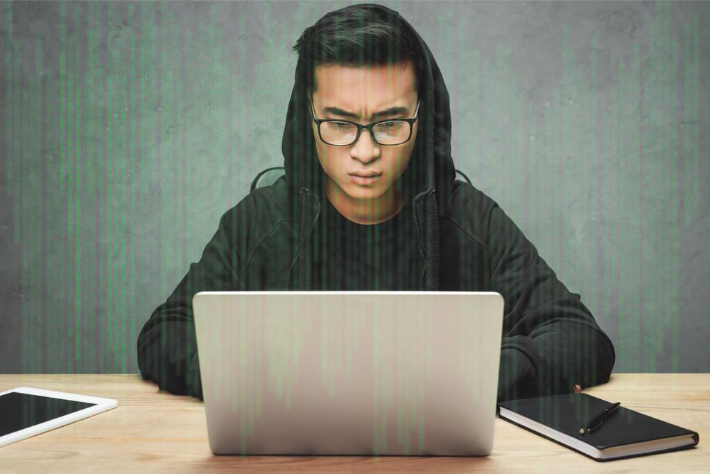 asiático hacker em óculos sentado à mesa, usando laptop e cercado com ilustração
  - Foto, Imagem