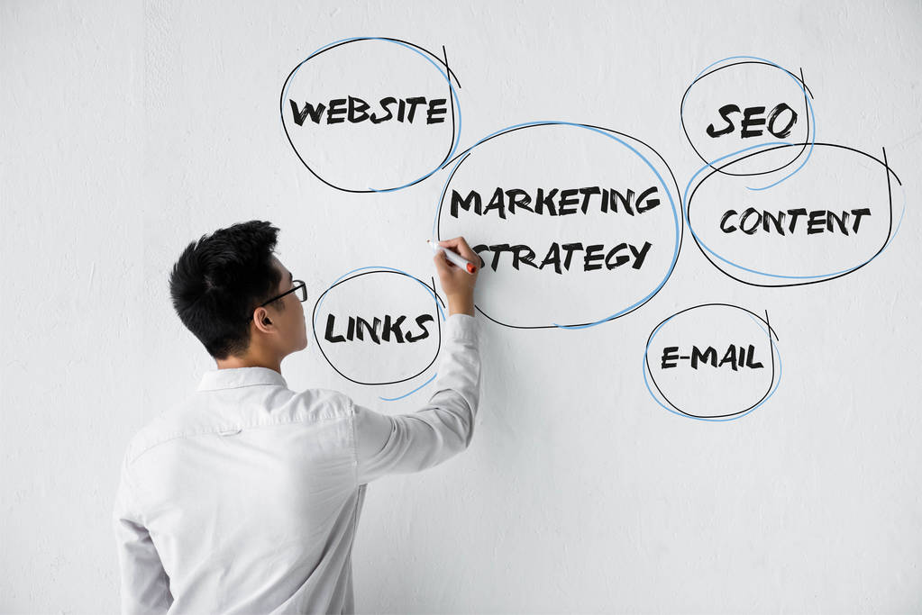 Обратный вид SEO менеджера, пишущего на стене с иллюстрацией концептуальных слов маркетинговой стратегии
  - Фото, изображение