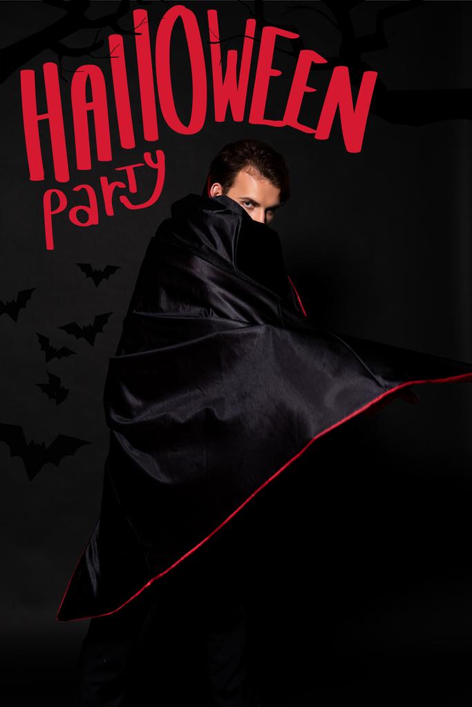 ハロウィンパーティーのイラストで黒の背景にマントで顔を覆う男 ロイヤリティフリー写真 画像素材
