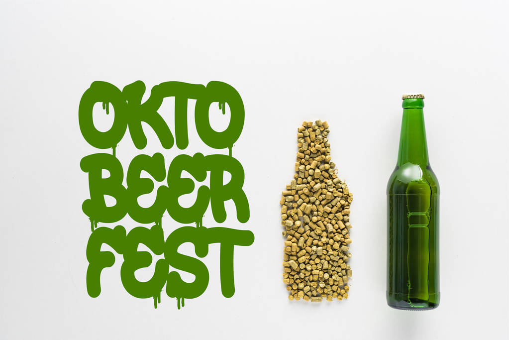 vue du dessus de la bouteille de bière près du houblon pressé et du lettrage vert Oktoberfest isolé sur blanc
  - Photo, image
