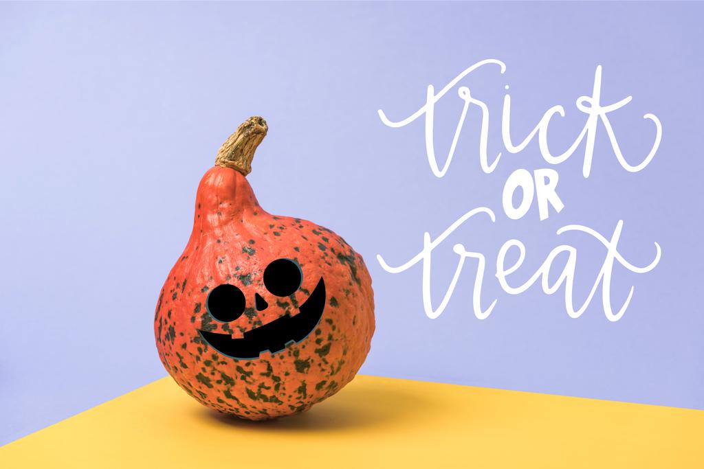 orange Halloween pumpkin on violet and yellow background with trick or treat lettering - Photo, Image