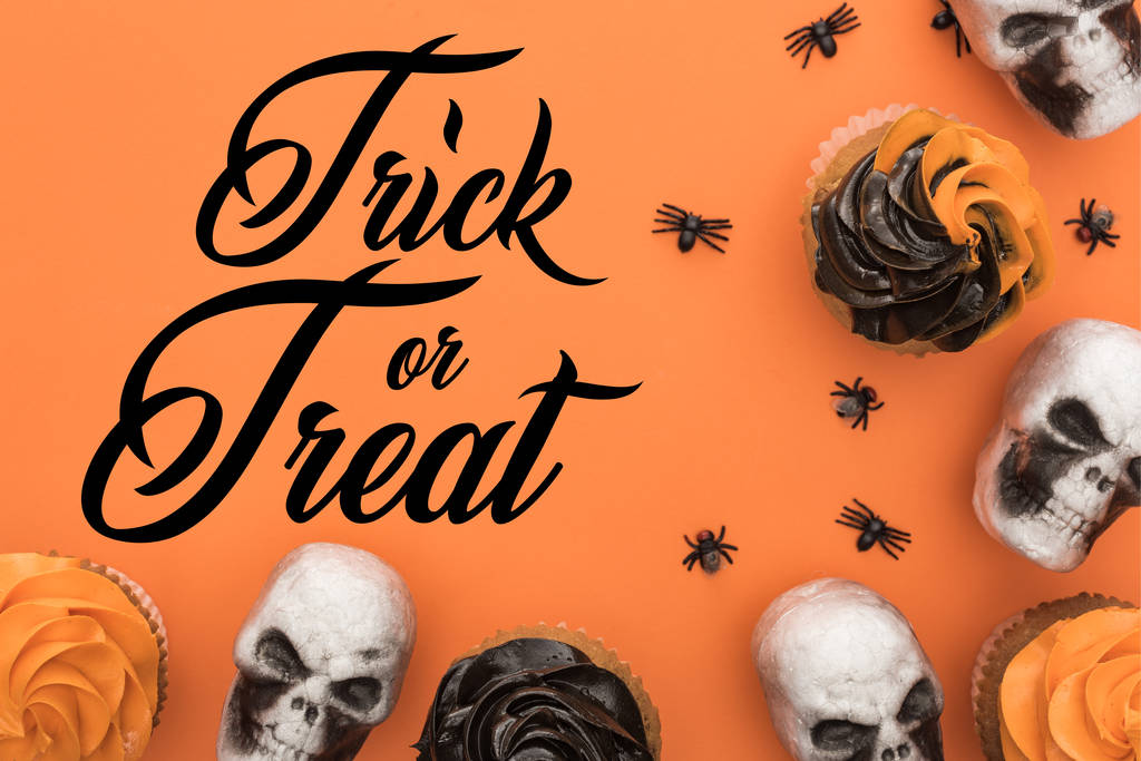 верхний вид вкусные кексы Хэллоуин с пауками и черепа на оранжевом фоне с трюком или лечения иллюстрации
 - Фото, изображение