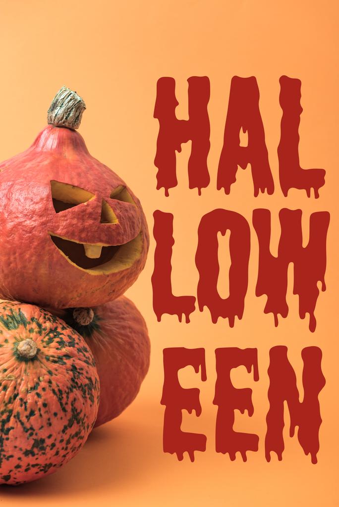 Gruselig geschnitzter Halloween-Kürbis auf orangefarbenem Hintergrund mit blutigem Halloween-Schriftzug - Foto, Bild