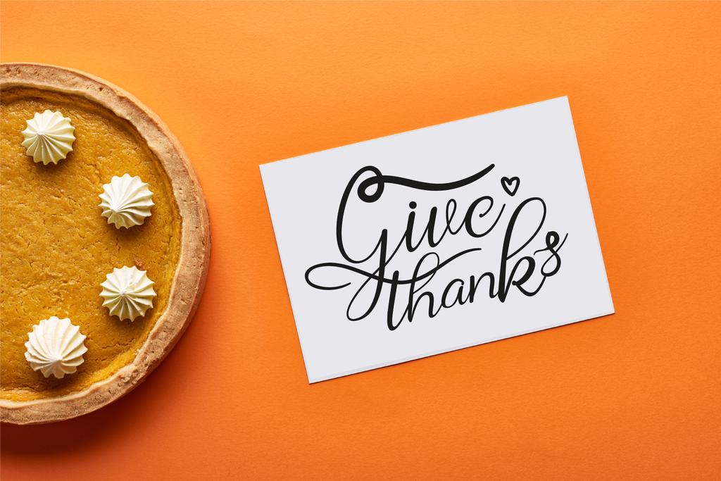 вид сверху на тыквенный пирог и открытку с благодарственной иллюстрацией на оранжевом фоне
 - Фото, изображение