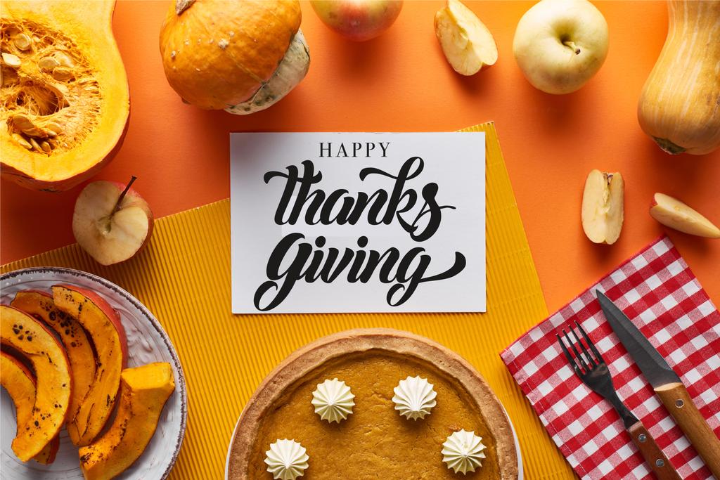 vista superior de pastel de calabaza, manzanas maduras y feliz tarjeta de acción de gracias sobre fondo naranja
 - Foto, imagen