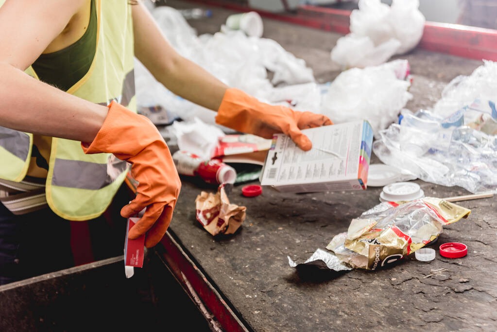 Werknemer die afvalinzameling in een moderne recyclinginstallatie scheidt - Foto, afbeelding