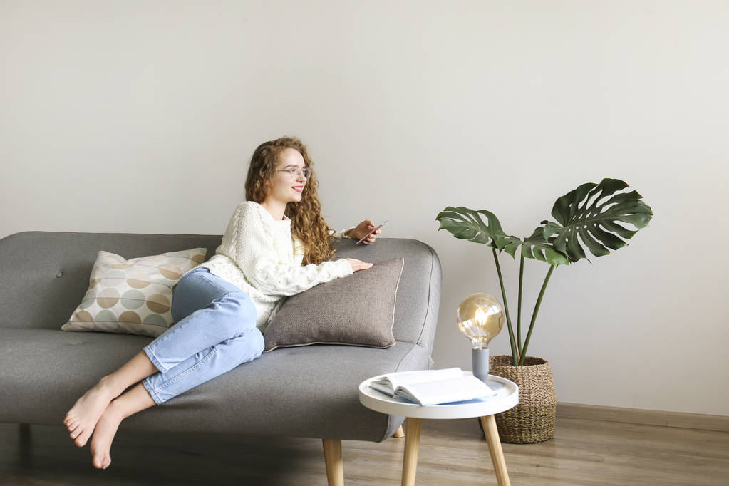 Кучеряве волосся брюнетка жінка розслабляється на дивані вдома
. - Фото, зображення