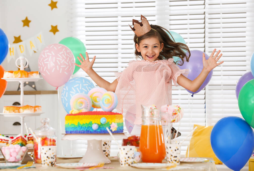 Счастливая девушка за столом с трепачами в комнате, украшенной к дню рождения
 - Фото, изображение