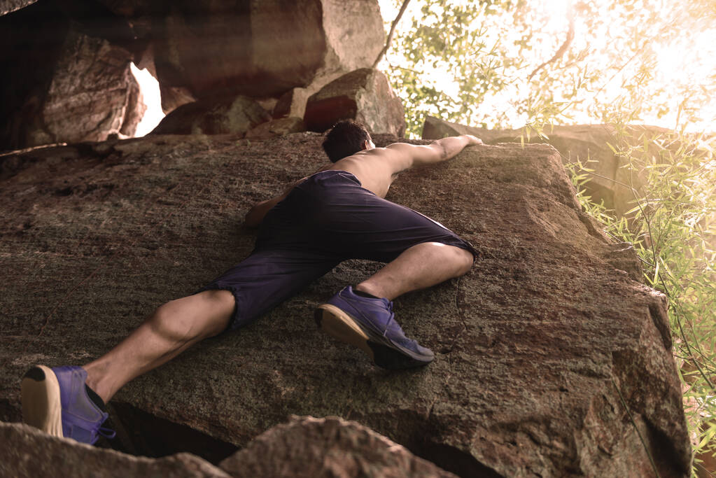 アジアのハンサムな男岩の山を登る - 写真・画像