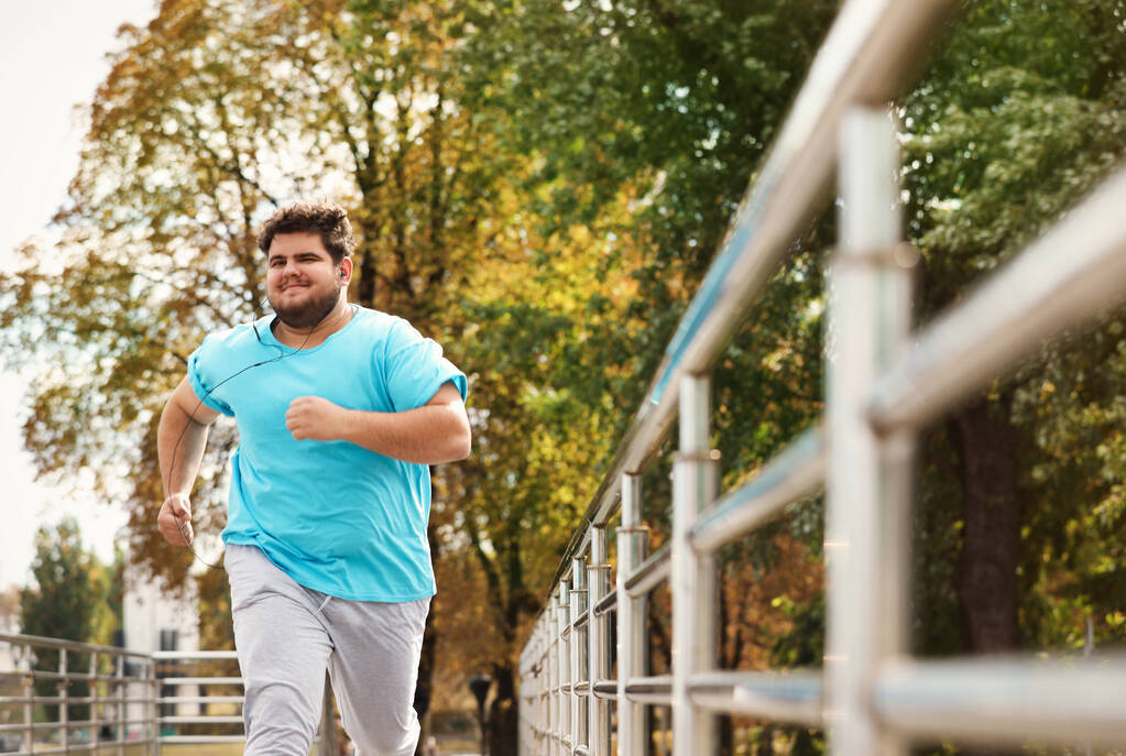 Ένας νεαρός υπέρβαρος άντρας τρέχει έξω. Τρόπος ζωής γυμναστικής - Φωτογραφία, εικόνα