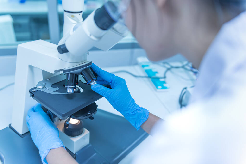 Jovem cientista asiático olhando através de um microscópio em um laboratory.Thailand pessoas fazendo alguma pesquisa
. - Foto, Imagem