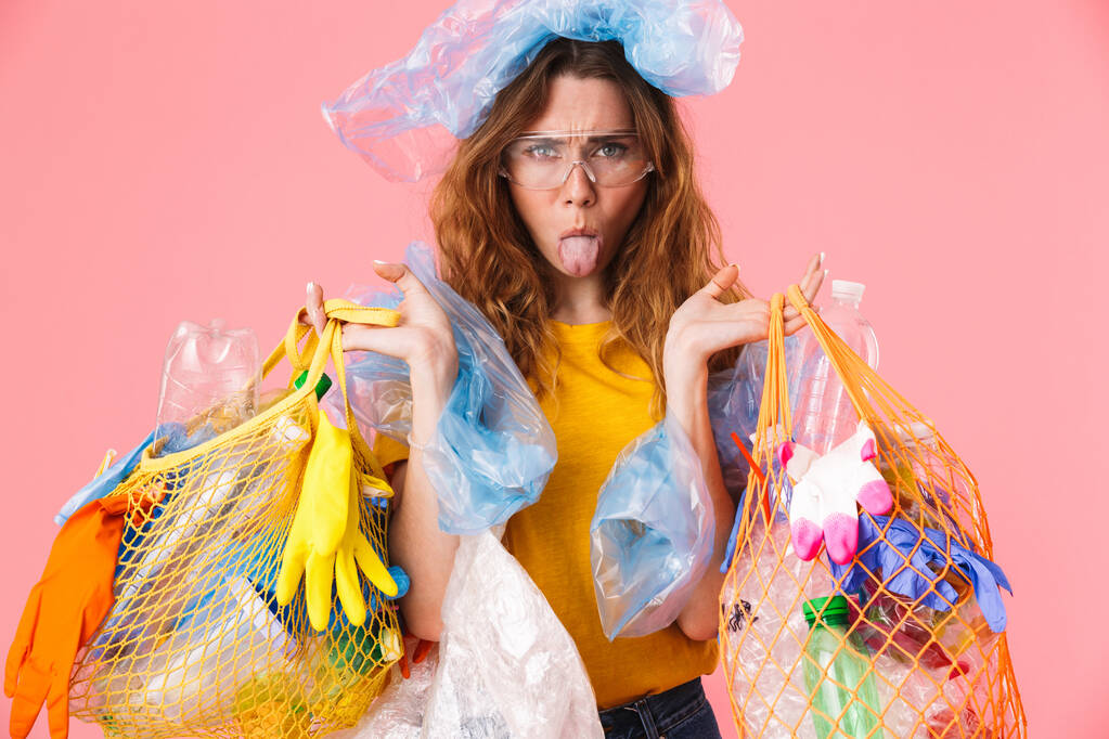 Foto einer Frau, die Tüten mit Plastikmüll in der Hand hält und die Zunge klebt - Foto, Bild